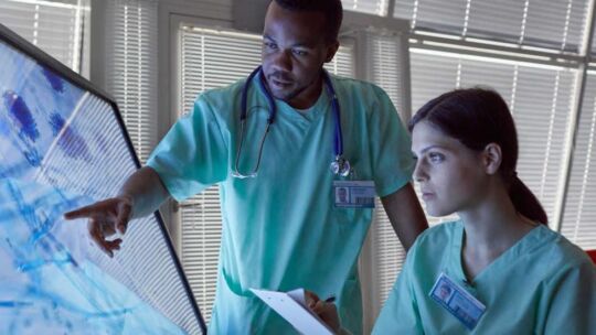 two healthcare professionals using large touchscreen