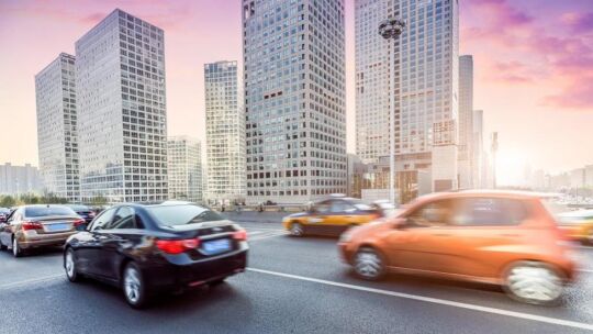 cars driving down a city street during sunrise