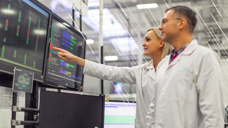 two manufacturing professionals analyzing data on a screen